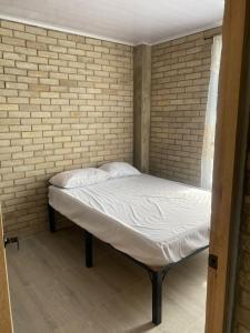 a bed in a room with a brick wall at El Rincón de Charito in Tumaco