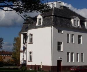 ein großes weißes Gebäude mit schwarzem Dach in der Unterkunft Hotel Okatex in Sagan