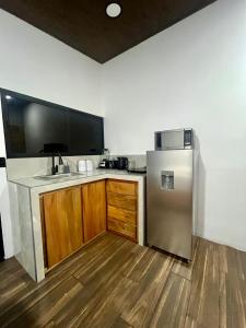 a kitchen with a stainless steel refrigerator and wooden cabinets at Arenal Rocks in Fortuna +6 photos