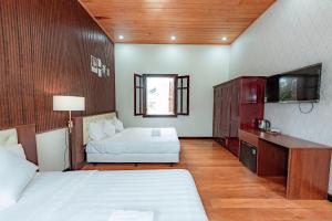 a hotel room with two beds and a tv at Biệt Thự Đà Lạt Nghỉ Dưỡng Gia Đình in Trai Mat