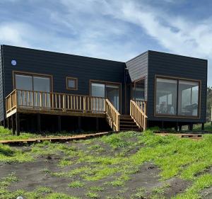 a black house with a porch and a deck at Casa Olas, Refugio Costero in Curanipe
