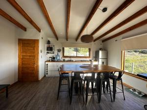 a kitchen with a wooden table and some chairs at Casa Olas, Refugio Costero in Curanipe +31 photos