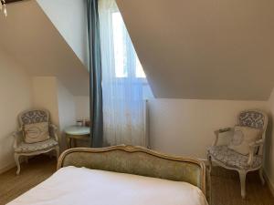 1 dormitorio con 2 sillas, 1 cama y 1 ventana en T2 Cosy et Confortable au coeur d'Aubusson, en Aubusson