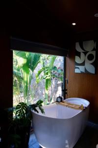 una bañera blanca frente a una ventana con una planta en Đòng Đòng Lodge, en Ấp Ðông Ðô