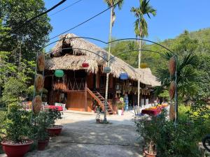 a building with a straw roof with plants in front at Bee Lucky Homestay in Hai Phong