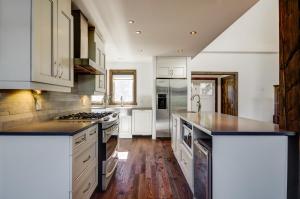 a kitchen with white cabinets and black counter tops at Luxury with hot tub 300mbps Wifi Games & more ! in Saint Adolphe D'Howard
