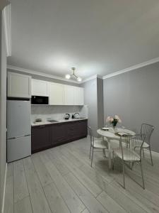 a kitchen and dining room with a table and chairs at Отличная квартира напротив ЭКСПО in Astana