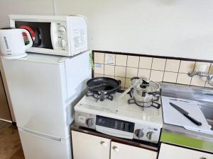 cocina con fogones blancos y microondas en 高平ハウス Room106, en Nagasaki