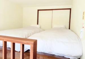 Dos camas en una habitación con sábanas blancas. en 高平ハウス Room106, en Nagasaki