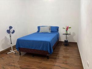a bedroom with a bed with blue sheets and a fan at XIMEL House in Flores