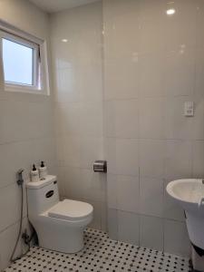 a white bathroom with a toilet and a sink at La nha Homestay in Da Lat