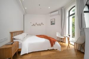 a white bedroom with a bed and a window at Gulangyu Sunlit Rock Garden Resort in Xiamen