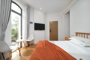 a white bedroom with a large bed and a tv at Gulangyu Sunlit Rock Garden Resort in Xiamen