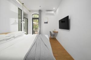 a white bedroom with a bed and a tv at Gulangyu Sunlit Rock Garden Resort in Xiamen