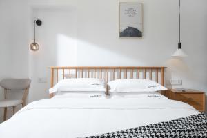 a bedroom with a large white bed with white pillows at Gulangyu Sunlit Rock Garden Resort in Xiamen