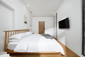 a white bedroom with a bed and a flat screen tv at Gulangyu Sunlit Rock Garden Resort in Xiamen