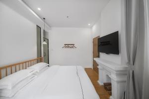 a white bedroom with a bed and a tv at Gulangyu Sunlit Rock Garden Resort in Xiamen