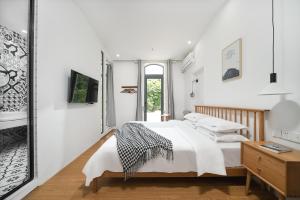 a white bedroom with a bed and a mirror at Gulangyu Sunlit Rock Garden Resort in Xiamen