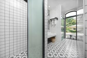 a bathroom with a shower and a white tiled floor at Gulangyu Sunlit Rock Garden Resort in Xiamen