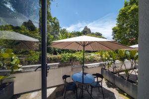 a table and chairs under an umbrella on a balcony at Gulangyu Sunlit Rock Garden Resort in Xiamen