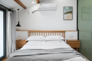 a bedroom with a bed with white sheets and pillows at Gulangyu Sunlit Rock Garden Resort in Xiamen