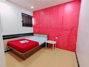 a bedroom with a red wall and a bed with a stool at Malhar Guest House in Pune