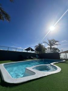 a swimming pool in the grass with the sun in the background at Narooma Palms Holiday Apartments in Narooma