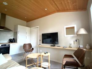 a living room with a tv on a wall at Charmant T2 RDC avec jardin privatif à 500m de Loctudy - FR-1-813-1 in Groix