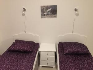- 2 lits dans une chambre avec des draps violets et une table de nuit dans l'établissement Lapland Koivusto Apartment, à Ranua
