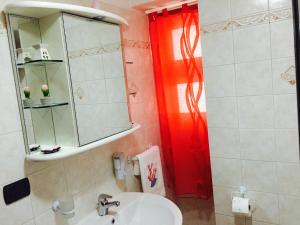 a bathroom with a sink and a red shower curtain at Corallia Apartment in Siracusa