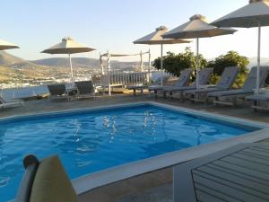 a swimming pool with chairs and umbrellas on a resort at Krotiri Bay -adults only in Parikia