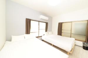 duas camas em um quarto com janela em 和ノ楓cottage第三 新宿の2階建て4室2シャワー2トイレ em Tóquio