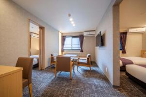 a hotel room with a table and chairs and a bed at RESI STAY Kuon in Kyoto