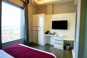 ein Schlafzimmer mit Bett, Schreibtisch und Fernseher in der Unterkunft Hotel Adsan Heights in Gajraula
