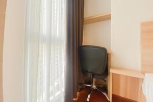 RawalembangModern Look Studio at Tokyo Riverside PIK 2 Apartment By Travelio的椅子坐在窗前,有窗帘