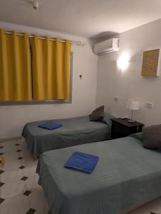 a room with two beds and a yellow curtain at El Marques Resort Townhouse in Puerto de Santiago +69 photos