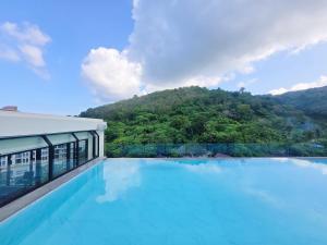 a swimming pool with a mountain in the background at Karon Utopia in Ban Karon