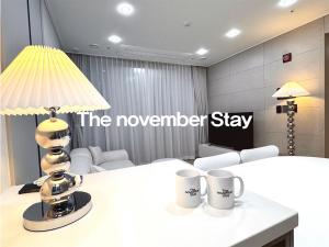 クリにあるThe November Stay Guri Stationのテーブル(ランプ付)とマグカップ2つ付