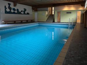 a large swimming pool with blue water in a building at Ferienwohnung Alpenglück mit Schwimmbad und Sauna in Oberstdorf