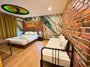 a room with two beds and a brick wall at Seeds Hotel Cheras Maluri in Kuala Lumpur