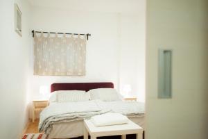 a white bedroom with a bed and a table at Fifty Apartments in Zagreb