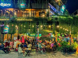 a crowd of people sitting at an outdoor restaurant at night at DMZ Hotel ,Central Hue ,Near Perfume River in Hue