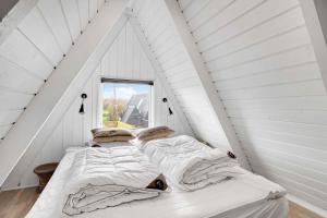 zwei Betten in einem weißen Zimmer mit Fenster in der Unterkunft Summer House At Himmerland Golf Resort in Farsø + 24 Fotos