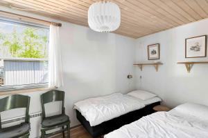 a bedroom with two beds and a window and a chandelier at Cottage In Peaceful Surroundings In Vester Sømark in Vester Sømarken