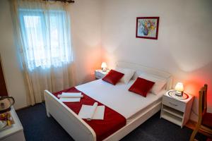 a bedroom with a large white bed with red pillows at Guest House Cesic in Dubrovnik