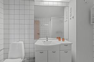 a white bathroom with a sink and a toilet at Cozy Holiday Apartment In The Center Of Søndervig Close To The North Sea in Ringkøbing +18 photos