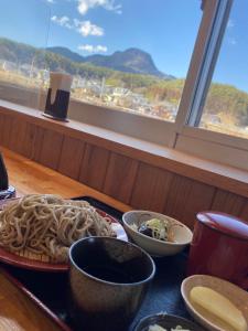 a table with plates of food and a window at TAZAWA BOSSA inn in Aoki