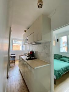 une cuisine avec des armoires blanches et un lit dans une chambre dans l'établissement Appartement entier avec une chambre proche Tour Eiffel, à Paris