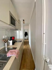 une cuisine avec des armoires blanches et un plancher en bois dans l'établissement Appartement entier avec une chambre proche Tour Eiffel, à Paris