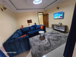 a living room with a blue couch and a television at The comfort 2 bedrooms pioneer in Eldoret